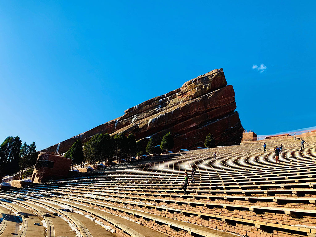 A few visitors walk down the bleachers at Red Rocks Amphitheatre on a nice sunny day. 